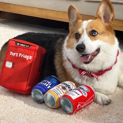 Corgi lying next to the plush Pup's Fridge toy and three plush beer-can squeaker toys